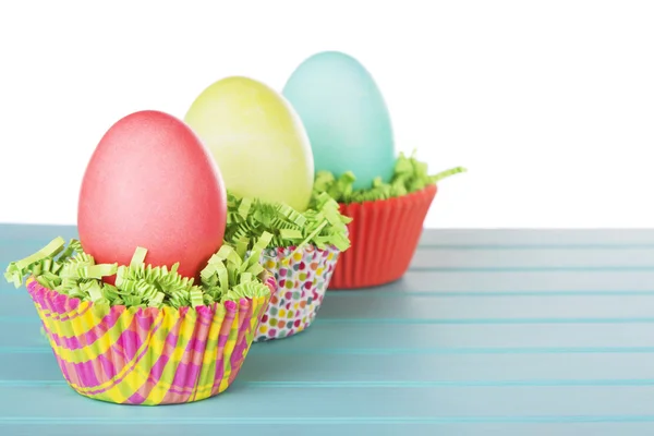 Dyed Easter eggs in a nest of green grass confetti and cup cake — Stock Photo, Image