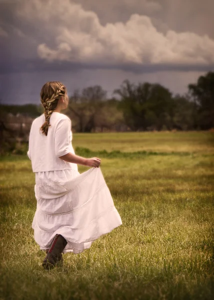 Chica vistiendo un vestido caminando en un pasto —  Fotos de Stock