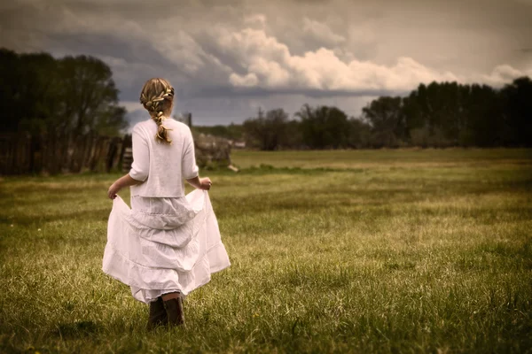 Chica vistiendo un vestido caminando en un pasto —  Fotos de Stock