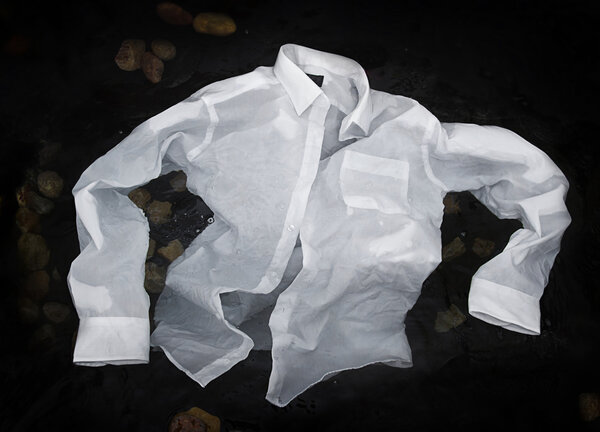 Мужская рубашка, плавающая или тонущая в воде
