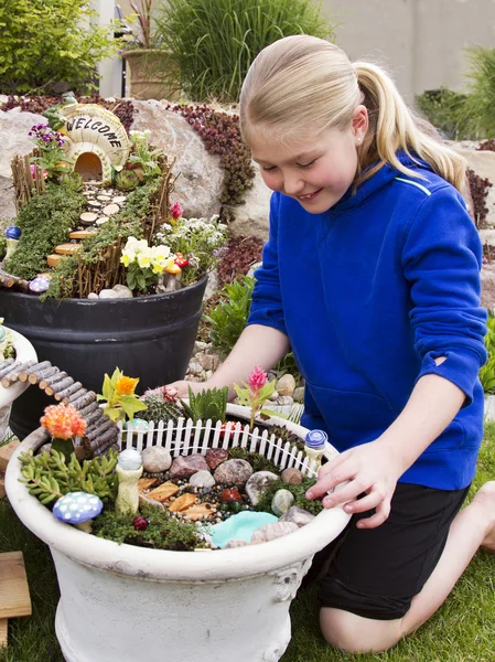 Young girl helping to make fairy garden in a flower pot — Stock Photo, Image