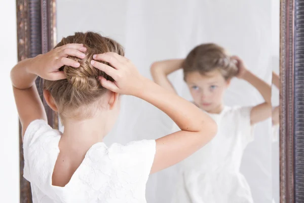 Criança consertando seu cabelo enquanto olha no espelho . — Fotografia de Stock