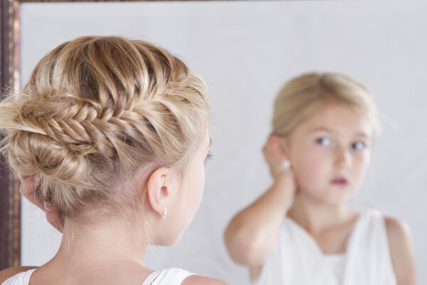 Child fixing her hair while looking in the mirror.