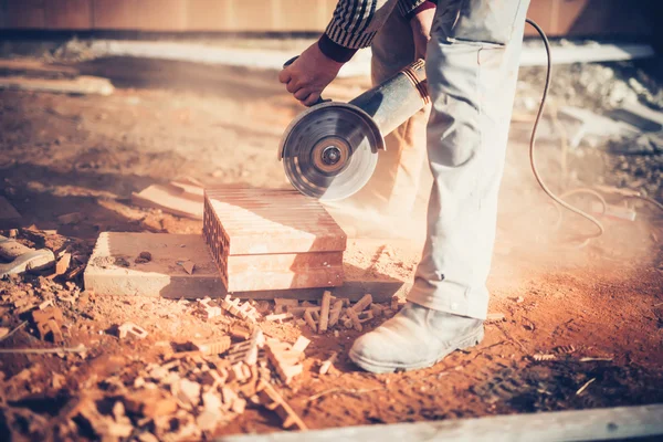 Trabalhador usando um moedor de ângulo no canteiro de obras para o corte de tijolos, detritos. Ferramentas e tijolos no novo canteiro de obras — Fotografia de Stock