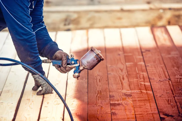 Industriële werknemer spuiten van verf op hout hout. Bouwvakker met spuitpistool — Stockfoto