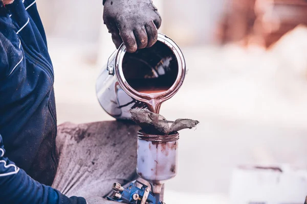 Industrial worker preparing paint for spraying with spray gun — Stock Photo, Image