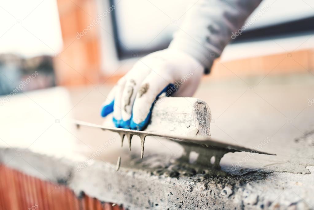 construction worker using steel trowel for plastering