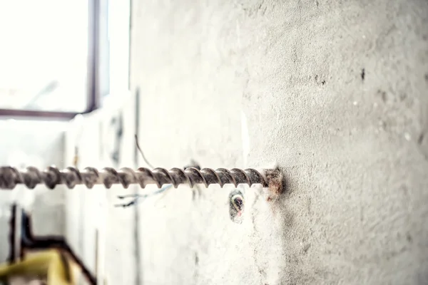 Primer plano de la maquinaria de perforación en el sitio de construcción. manitas utilizando una máquina de perforación de martillo neumático para hacer agujeros en la pared interior de hormigón — Foto de Stock