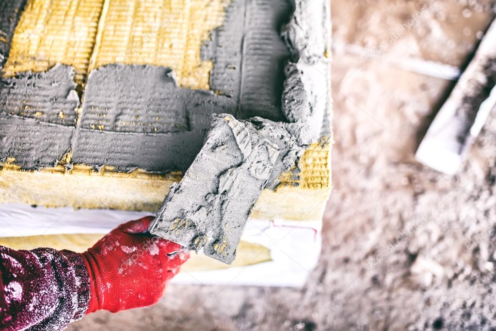 close-up of worker hand on industrial construction site using a trowel and applying adhesive on thermal insulation panels