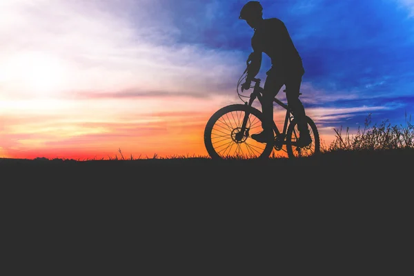 Veduta del ciclista in piedi con mountain bike sul sentiero in collina al tramonto — Foto Stock