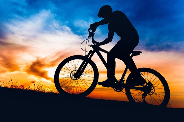 Uomo in mountain bike al tramonto, in sella alla bicicletta sulle colline — Foto Stock