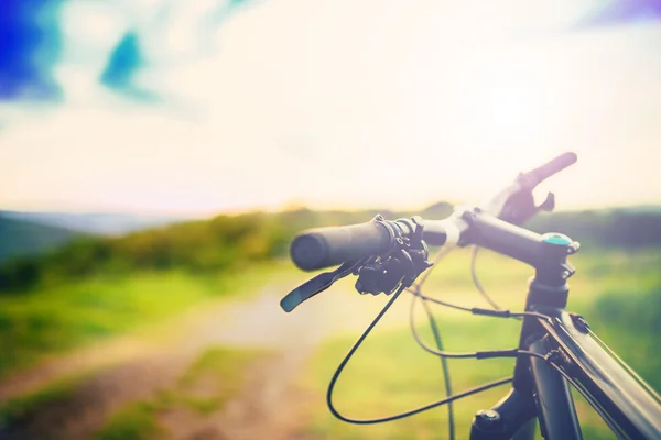 Mountain bike maniglia bar al tramonto sul sentiero di montagna. dettagli sulle attività sportive — Foto Stock