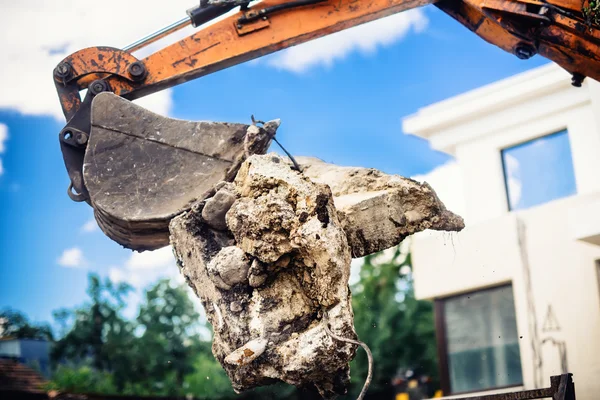 Pelle sur site de démolition chargement blocs de béton — Photo