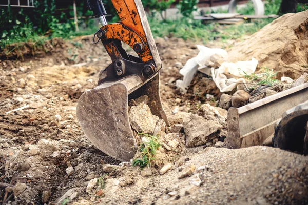 Industrial backhoe excavator with close-up of metal bucket moving earth at construction site — Stock Photo, Image