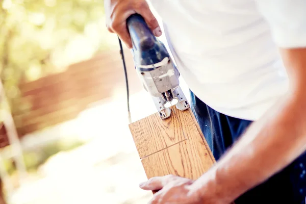 Männlicher Arbeiter schneidet bei Renovierung mit Stichsäge Holzparkett — Stockfoto