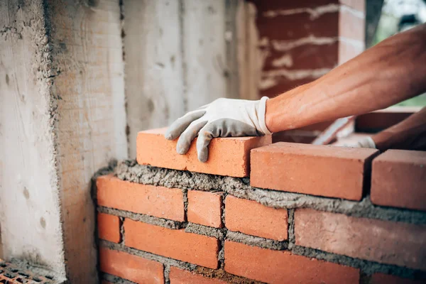 Trabalhador da construção civil que coloca tijolos em paredes exteriores — Fotografia de Stock