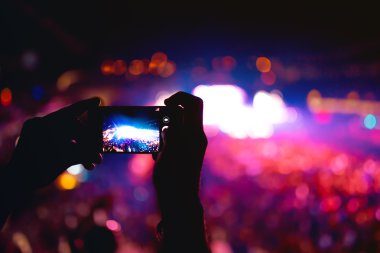 Müzik konser, festival fotoğraf ve video çekmek için kamera telefon kullanarak eller silüeti. Fotoğraf üzerinde yumuşak etkisi