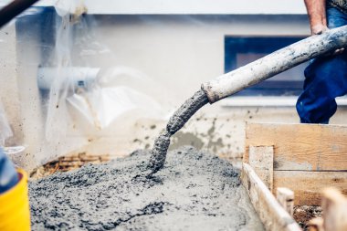 Elle pompa tüpüyle çimento döken endüstriyel işçiler