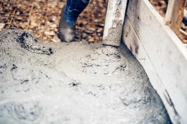 Närbild av cement pump rör på industriella byggarbetsplats med arbetstagare hantering — Stockfoto