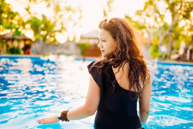 Havuz kenarında oturan ve yaz zevk mayo modaya uygun güzel ve seksi esmer. 