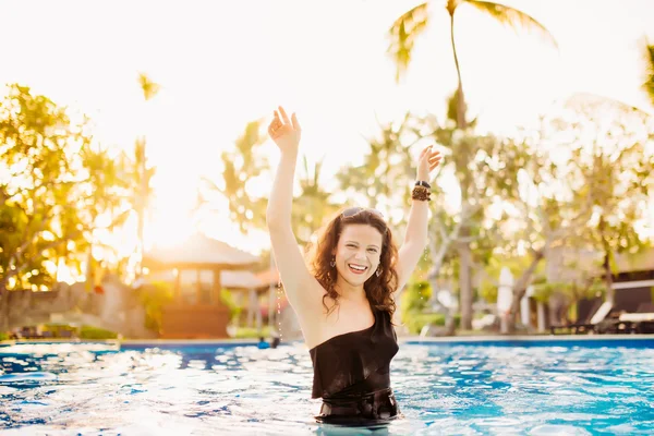 Schöne brünette Frau, die Wasser im sexy Bikini am Pool planschen lässt. schlanke Bräunungsfrau, die Spaß im Pool hat und Wasser mit den Armen planschen lässt. Urlaubsstimmung im Sommer. — Stockfoto