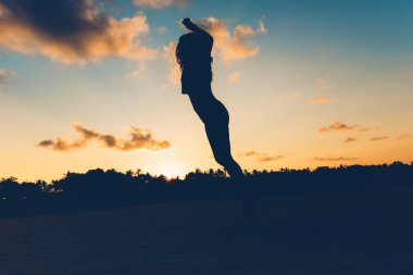 Güzel esmer sahilde günbatımı, kaygısız ve stres özgür kadın adada atlama siluet. 