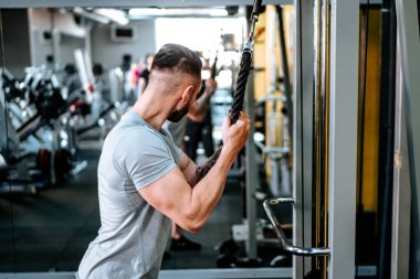 Spor salonunda kol pazılarını çalıştıran kaslı bir adam. Fitness hayatı, sağlıklı yaşam konsepti