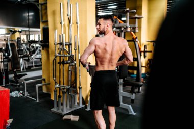 Vücut geliştiren yakışıklı güçlü atletik adam sırt kaslarında çalışıyor. Spor fitness ve vücut geliştirme sağlıklı konsept
