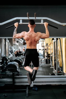 Sporcu tişörtsüz adam spor salonunda fitness eğitimi alıyor.
