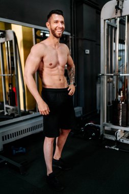 Gülümseyen vücut geliştirici antrenman yapıyor ve gülüyor. Sağlıklı yaşam tarzı