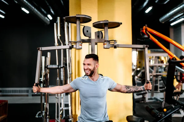 Man in sport gear working out and smiling at gym. Bodybuilding details, fitness workou and healthy lifestyle detail