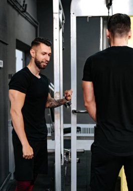 İki adam spor yapıyor, kişisel antrenör müşteriye sektörde yardımcı oluyor.