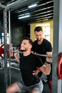 Spor salonunda müşterilere yardım eden ve yardımcı olan erkek antrenör portresi. Sağlıklı yaşamın sağlık detayları