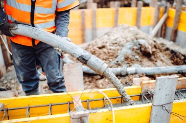 İnşaat sırasında dökülen betonun detayları. Endüstriyel detaylar, makineler, insanlar ve araçlar