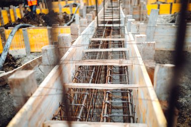 Ev, bina, detaylar ve çelik parmaklıklar ve ahşap kaplamalı tel çubuklarla takviye birlikleri, çimento dökülmesine hazırlanıyor.