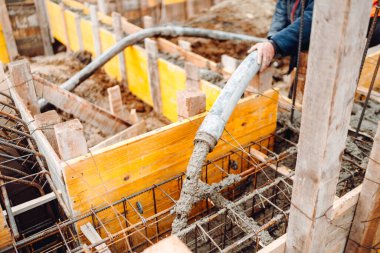 beton otomatik pompa çalışıyor ve ev inşaatında ahşap çerçevelere çimento dökülüyor