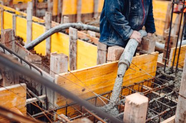 İnşaat sırasında dökülen betonun detayları. Endüstriyel detaylar, makineler, insanlar ve araçlar