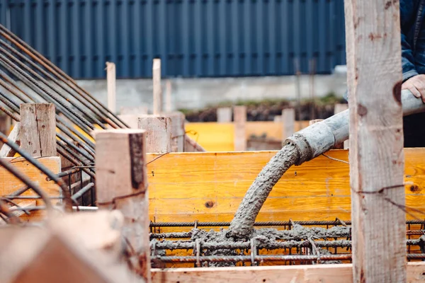 workers pouring concrete with concrete pump. Details of construction site and close up details of worker workwear