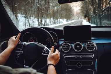 Caucasian man driving car on the empty road, winter and snow backgroun