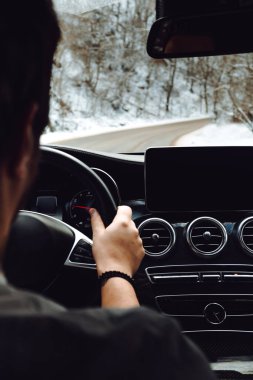 Portrait of man going for a drive with brand new modern car, forest road winter details