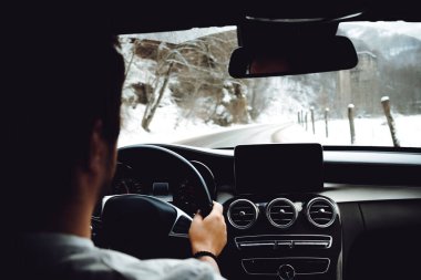 Portrait of man going for a drive with new modern car, forest road winter details