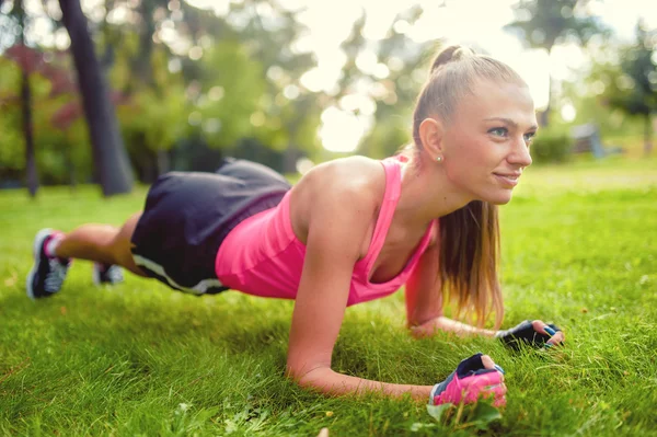 Mulher fitness alongamento e trabalhar no parque, na grama — Fotografia de Stock