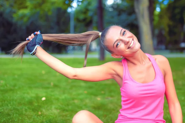 Souriant fille blonde jouer avec les cheveux tout en travaillant dans le parc — Photo