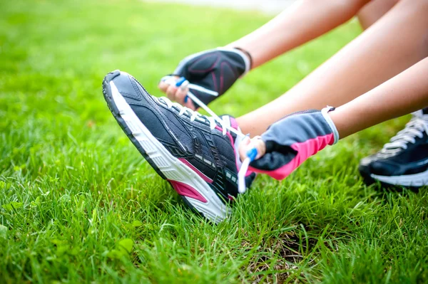 Primer plano de la corredora activa, preparando zapatos para entrenar y hacer ejercicio en el parque de fitness urbano — Foto de Stock