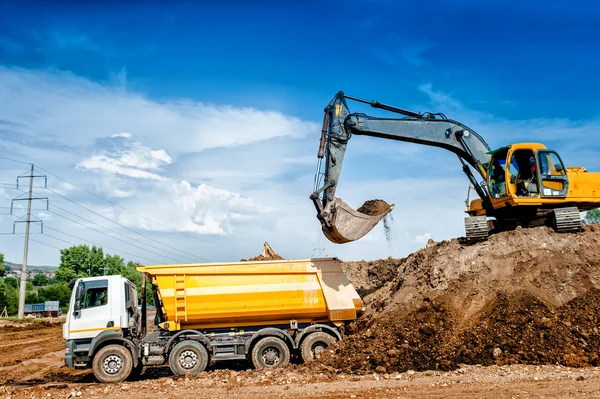 Industrial truck loader excavator and bulldozer moving earth and unloading into a dumper truck — Stock Image Industrial truck loader excavator and bulldozer moving earth and unloading into a dumper truck Royalty Free Stock Images