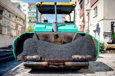 Industrial paver laying fresh asphalt and bitumen pavement on top of gravel layer during road construction clipart