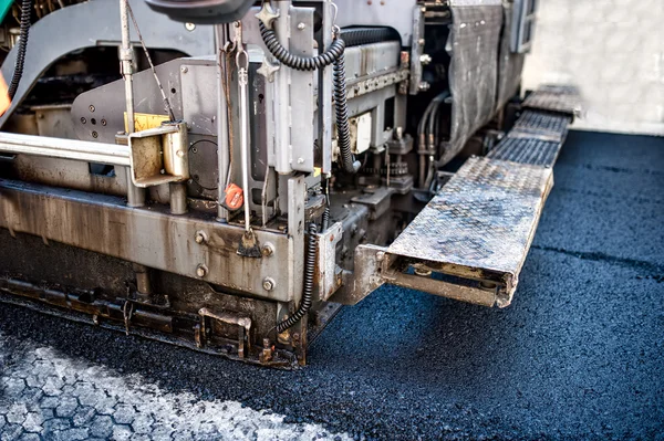 Máquina de pavimento que pone asfalto fresco o betún en la parte superior de la base de grava durante la construcción de carreteras o reparación de carreteras —  Fotos de Stock
