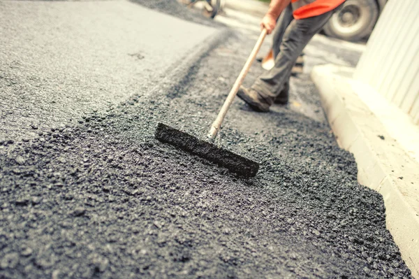 Trabajador nivelando asfalto fresco en un sitio de construcción de carreteras, edificios industriales y trabajo en equipo. Efecto Vintage — Foto de Stock