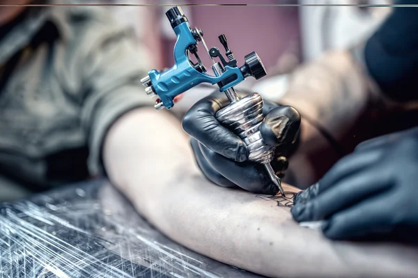 Tattoo artist drawing on client with special tools — Stock Photo, Image