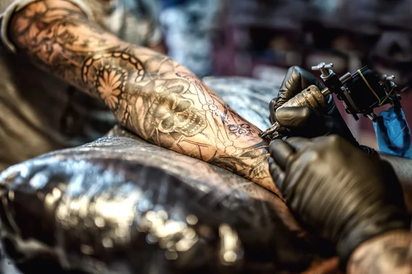 Dibujo del artista del tatuaje en el brazo y en la piel del cliente Imágenes De Stock Sin Royalties Gratis